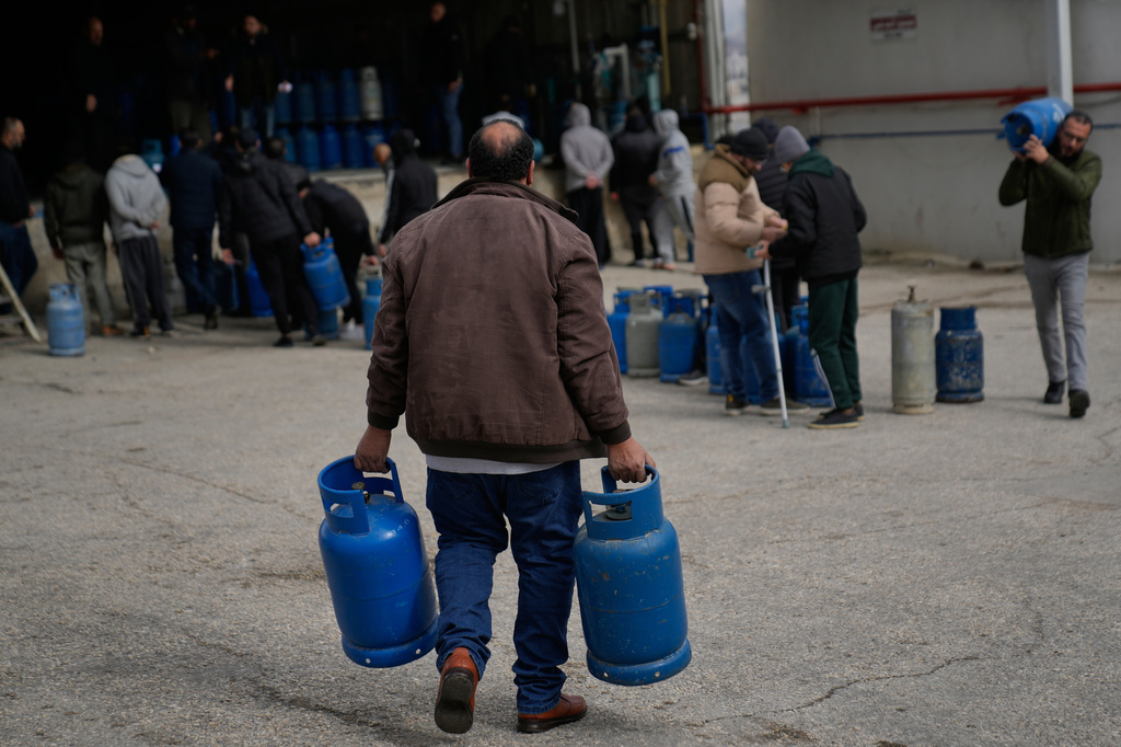 FILE - A Palestinian man carries his empty cooking gas cylinders, while he arrives at the main LPG station, as the occupied West Bank suffers a cooking gas shortage due to the decline of deliveries from the Israeli suppliers during the past three weeks, in the city of Beitunia, Friday, Jan. 23, 2026. (AP Photo/Nasser Nasser, File)