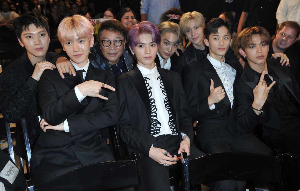 FILE - Producer Lee Soo Man, third from left, and members of SuperM, from left, Ten, Baekhyun, Taeyong, Kai, Taemin, Mark and Lucas sit in the audience to watch the premiere of their music video for their song "Jopping" during a media conference on Oct. 3, 2019, at Capitol Studios in Los Angeles. (Photo by Richard Shotwell/Invision/AP, File)