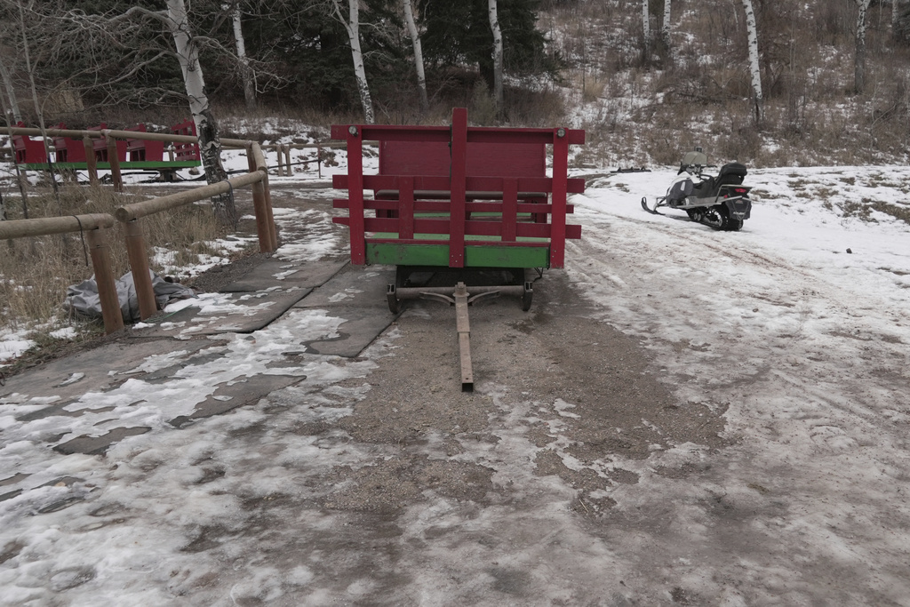 An sleigh rests by a stable, unable to be used with minimal snow cover Thursday, Dec. 18, 2025, in Edwards, Colo. (AP Photo/Brittany Peterson)