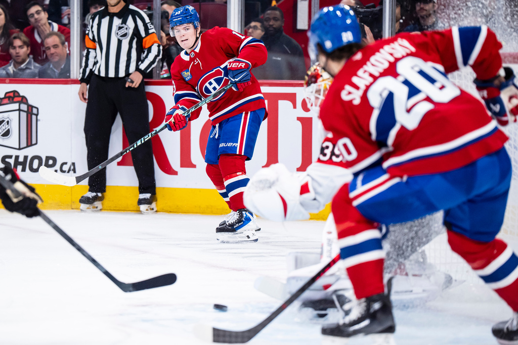 Montreal Canadiens' Cole Caufield, left, passes to teammate Juraj Slafkovský (20) in front of the net during the first period of an NHL hockey game against the Ottawa Senators in Montreal, Tuesday, Dec. 2, 2025. (Christopher Katsarov/The Canadian Press via AP)