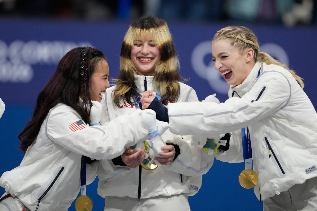 From left, Ellie Kam, Alysa Liu, and Amber Glenn of Team USA react after receiving their gold medals for the figure skating team event at the 2026 Winter Olympics, in Milan, Italy, Sunday, Feb. 8, 2026. (AP Photo/Ashley Landis)