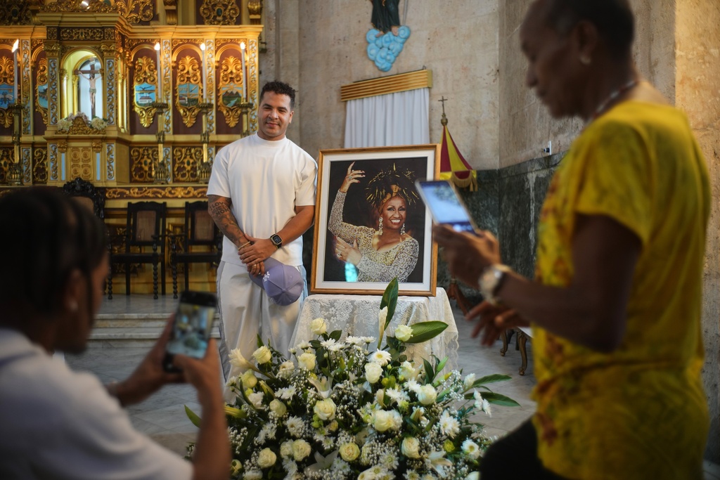 Cuban reggaeton artist Yomil poses for a photo beside a framed image of late singer Celia Cruz after attending a memorial Mass marking the centennial of her birth at the Virgen del Cobre or Our Lady of Charity church in Havana, Tuesday, Oct. 21, 2025. (AP Photo/Ramon Espinosa)
