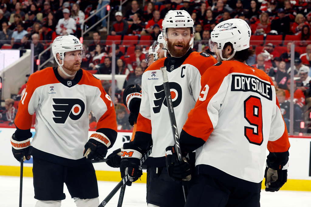 Philadelphia Flyers' Sean Couturier (14) talks with Jamie Drysdale (9) as Carl Grundstrom (91) looks on prior to a face-off during the second period of Game 2 of an NHL hockey Stanley Cup second-round playoff series against the Carolina Hurricanes in Raleigh, N.C., Monday, May 4, 2026. (AP Photo/Karl DeBlaker)