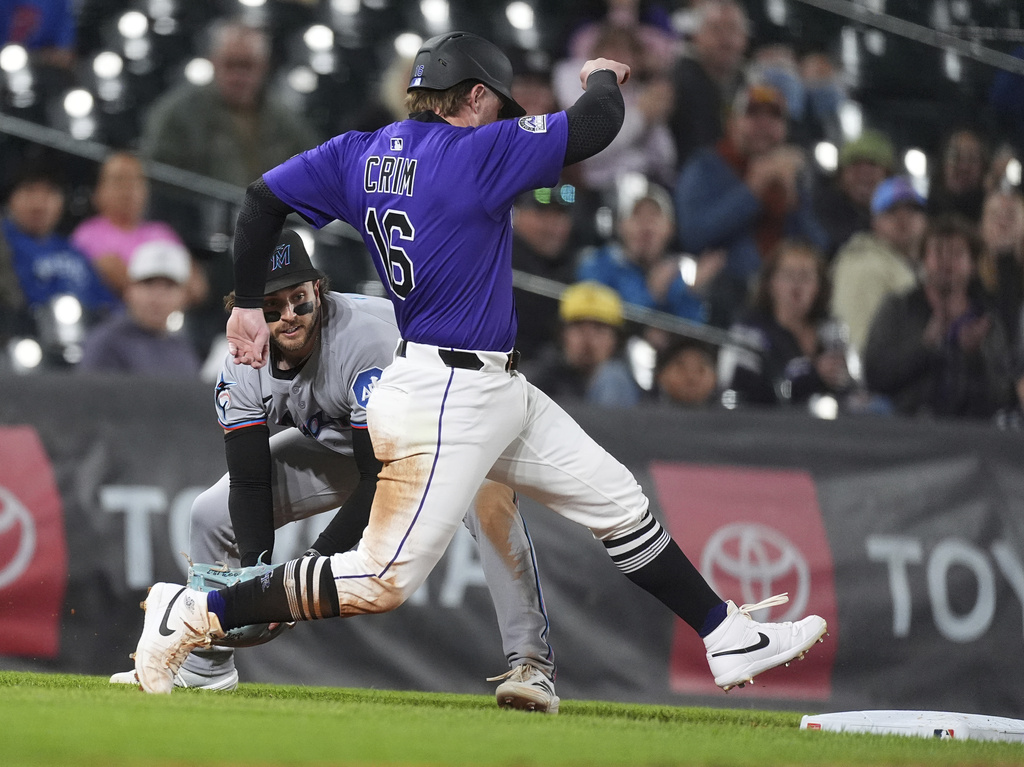 Colorado Rockies' Blaine Crim, front, hurries back to third base as Miami Marlins third baseman Connor Norby fields the throw in the second inning of a baseball game Wednesday, Sept. 17, 2025, in Denver. (AP Photo/David Zalubowski)