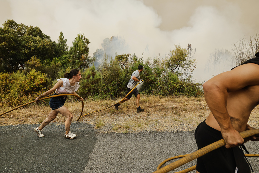Local residents and volunteers work together to battle an encroaching wildfire in Larouco, northwestern Spain, Aug. 13, 2025. (AP Photo/Lalo R. Villar)
