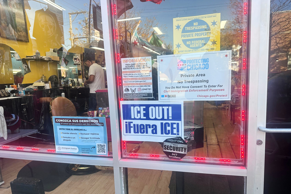A sign reads "ICE OUT" and informs people of their rights outside a barbershop on Tuesday, October, 28, 2025 in Chicago. (AP Photo/Elliot Spagat)