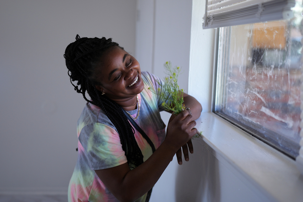 Haitian immigrant Nicole, who works at a meat processing plant, holds wildflowers she picked near her apartment, April 13, 2025, in Dumas, Texas. (AP Photo/Eric Gay, File)