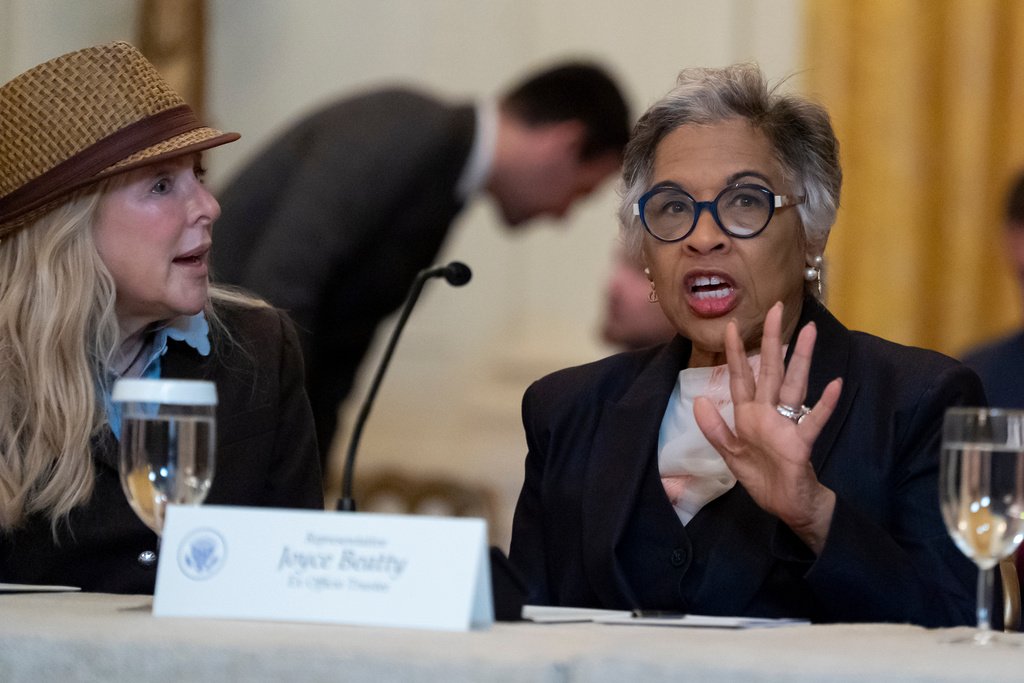 Mindy Levine, left, listens as Rep. Joyce Beatty, D-Ohio, talks before President Donald Trump arrives for a board meeting of the John F. Kennedy Memorial Center For The Performing Arts in the East Room of the White House, Monday, March 16, 2026, in Washington. (AP Photo/Alex Brandon)