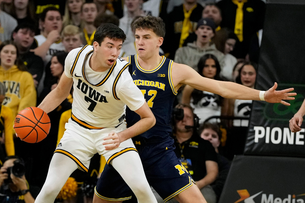Iowa forward Alvaro Folgueiras (7) drives around Michigan forward Will Tschetter during the first half of an NCAA college basketball game, Thursday, March 5, 2026, in Iowa City, Iowa. (AP Photo/Charlie Neibergall)