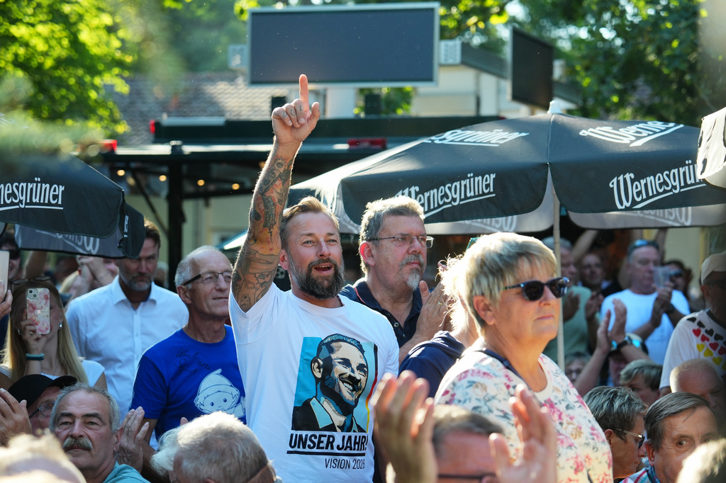 Supporters applause to Ulrich Sigmund, the top candidate for the "Alternative for Germany" (AfD) party in the state elections in Saxony-Anhalt, during his speech at a campaign barbecue hosted by the party in Moeser, Germany, Thursday, Aug. 13, 2026. (AP Photo/Markus Schreiber)