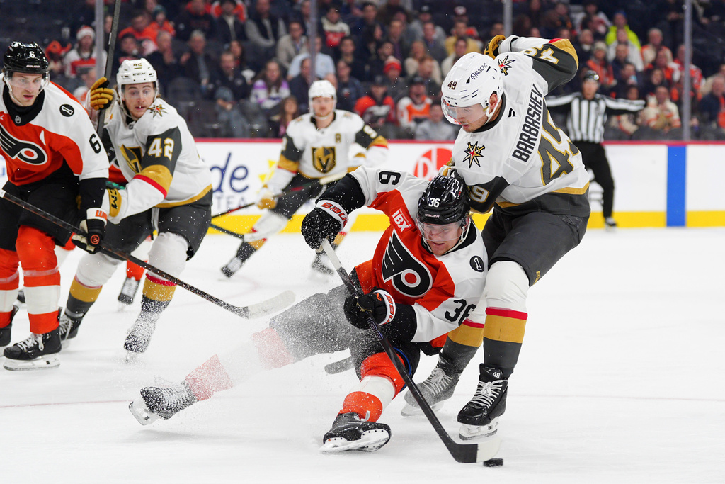 Philadelphia Flyers' Emil Andrae, center, is tripped by Vegas Golden Knights' Ivan Barbashev (49) during the first period of an NHL hockey game, Thursday, Dec. 11, 2025, in Philadelphia. (AP Photo/Derik Hamilton)