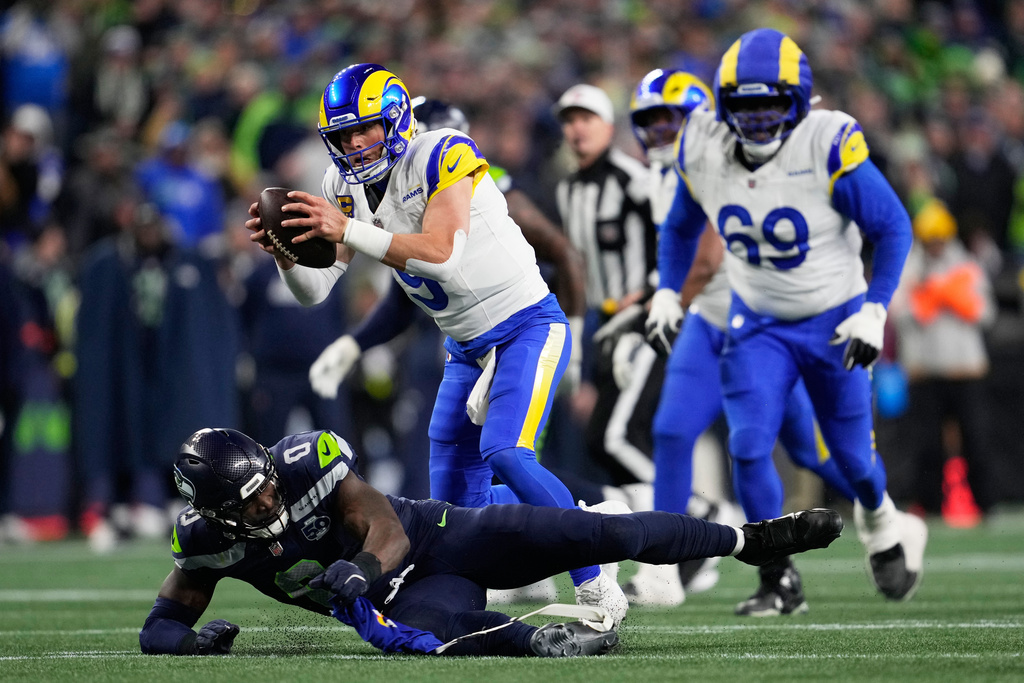 Los Angeles Rams quarterback Matthew Stafford (9) runs over Seattle Seahawks linebacker DeMarcus Lawrence (0) during the second half of the NFC Championship NFL football game Sunday, Jan. 25, 2026, in Seattle. (AP Photo/Godofredo A. Vásquez)