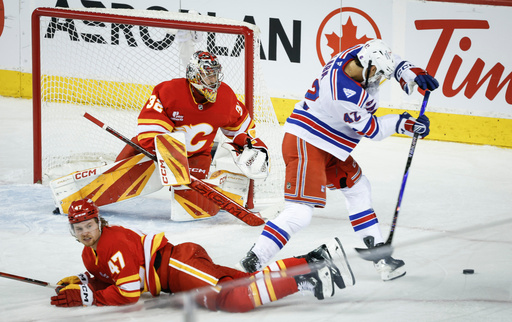 New York Rangers' Noah Laba, right, gets past Calgary Flames' Connor Zary (47) as Flames goalie Dustin Wolf, top left, looks on during third-period NHL hockey game action in Calgary, Alberta, Sunday, Oct. 26, 2025. (Jeff McIntosh/The Canadian Press via AP) New York Rangers' Noah Laba, right, gets past Calgary Flames' Connor Zary (47) as Flames goalie Dustin Wolf, top left, looks on during third-period NHL hockey game action in Calgary, Alberta, Sunday, Oct. 26, 2025. (Jeff McIntosh/The Canadian Press via AP)