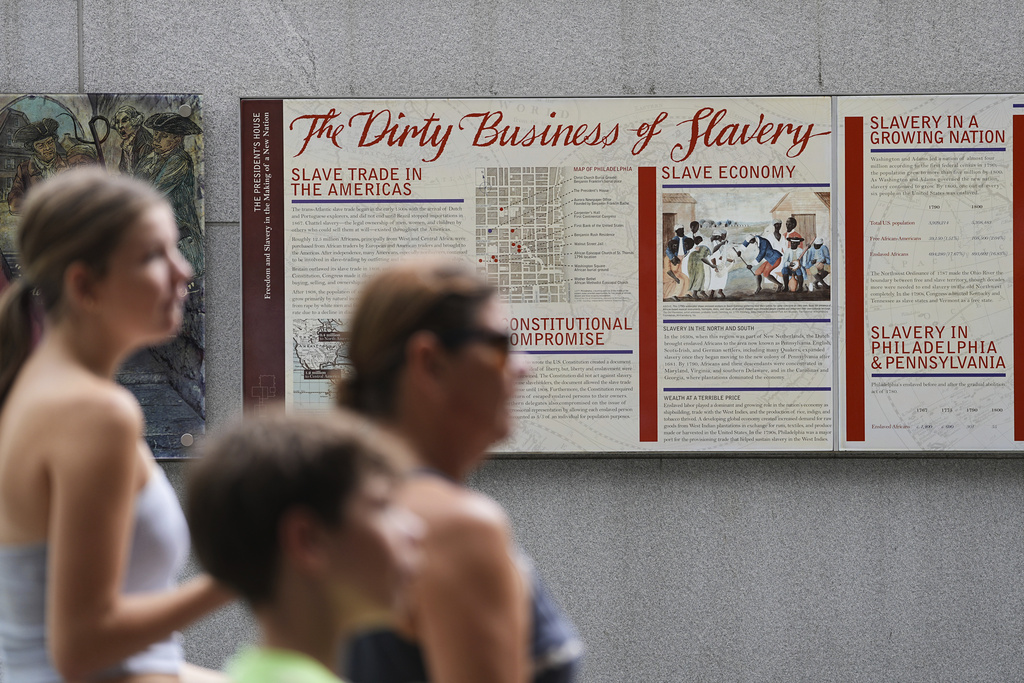 People walk past an informational panel at President's House Site Tuesday, Aug. 19, 2025, in Philadelphia. (AP Photo/Matt Rourke)