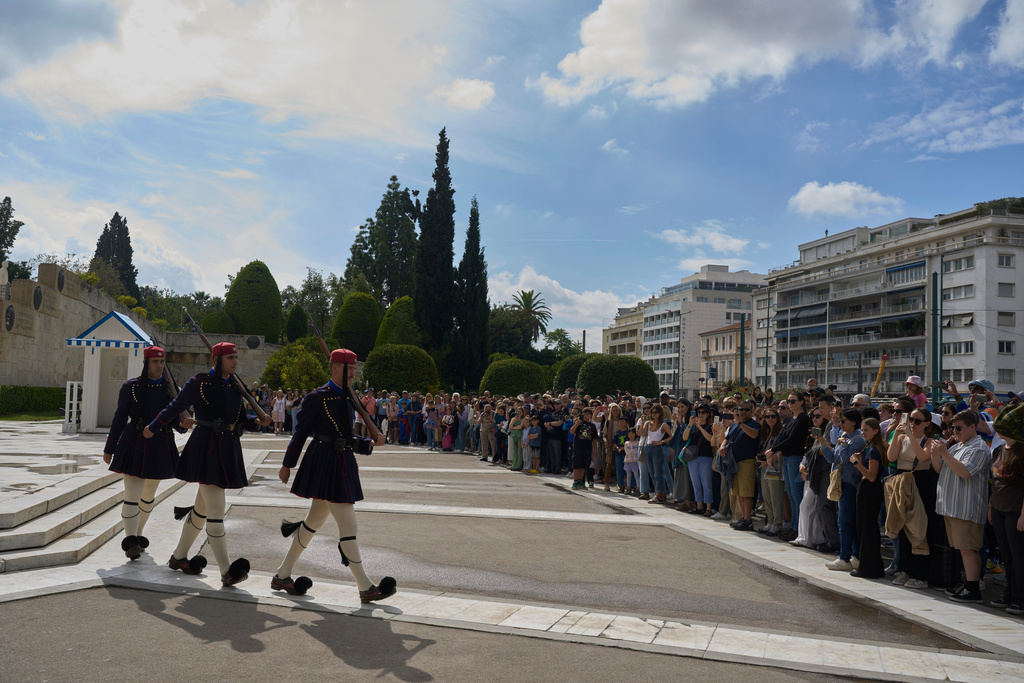 Tourists watch the changing of the guard at the Tomb of the Unknown Soldier in front of the Greek parliament, in Athens, Tuesday, Oct. 21, 2025, as lawmakers debate regulations to protect the monument, recently the focus of protests by relatives of victims of Greece's deadliest train crash. (AP Photo/Petros Giannakouris)