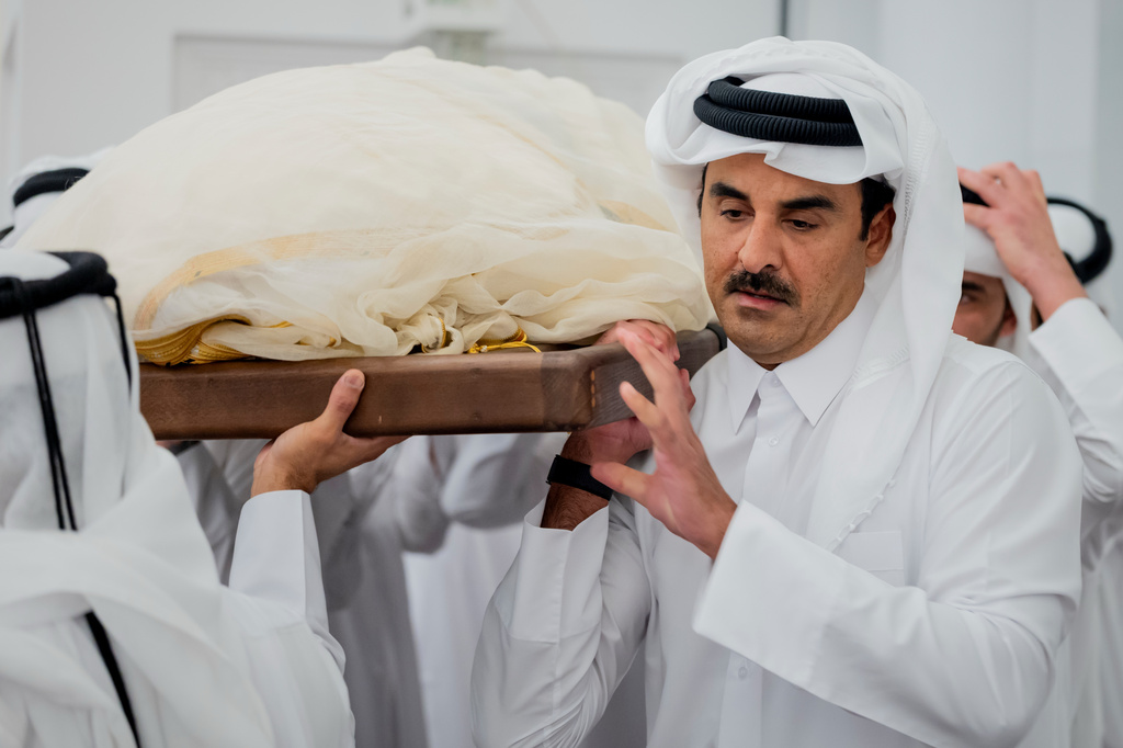 In this picture released by the Qatar Amiri Diwan media office, Qatari Emir Sheikh Tamim bin Hamad Al Thani helps carry the body of his father, Qatar's former ruler Sheikh Hamad bin Khalifa Al Thani, with other mourners for a funeral prayer at the Mohammed bin Abdulwahab Mosque in Doha, Qatar, Sunday, July 12, 2026. (Qatar Amiri Diwan via AP)