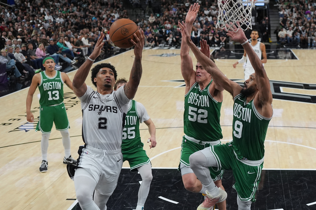 San Antonio Spurs guard Dylan Harper (2) drives to the basket against Boston Celtics guard Derrick White (9) and center Luka Garza (52) during the second half of an NBA basketball game in San Antonio, Tuesday, March 10, 2026. (AP Photo/Eric Gay)
