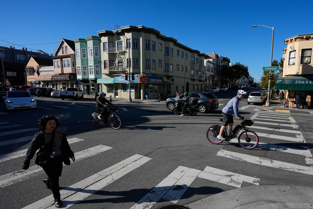 People travel on the intersection of Clement Street and 25th Avenue in the Richmond District, Friday, Oct. 17, 2025, in San Francisco. (AP Photo/Godofredo A. Vásquez)