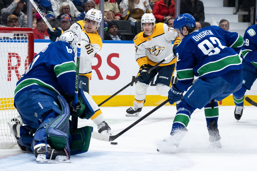 Nashville Predators' Zachary L'heureux (68) and Luke Evangelista (77) watch as Vancouver Canucks' Liam Ohgren (92) tips in the puck from Nashville's Matthew Wood, not seen, past Vancouver goaltender Nikita Tolopilo (60) during the second period of an NHL game in Vancouver, on Thursday, March 12, 2026. (Ethan Cairns/The Canadian Press via AP)