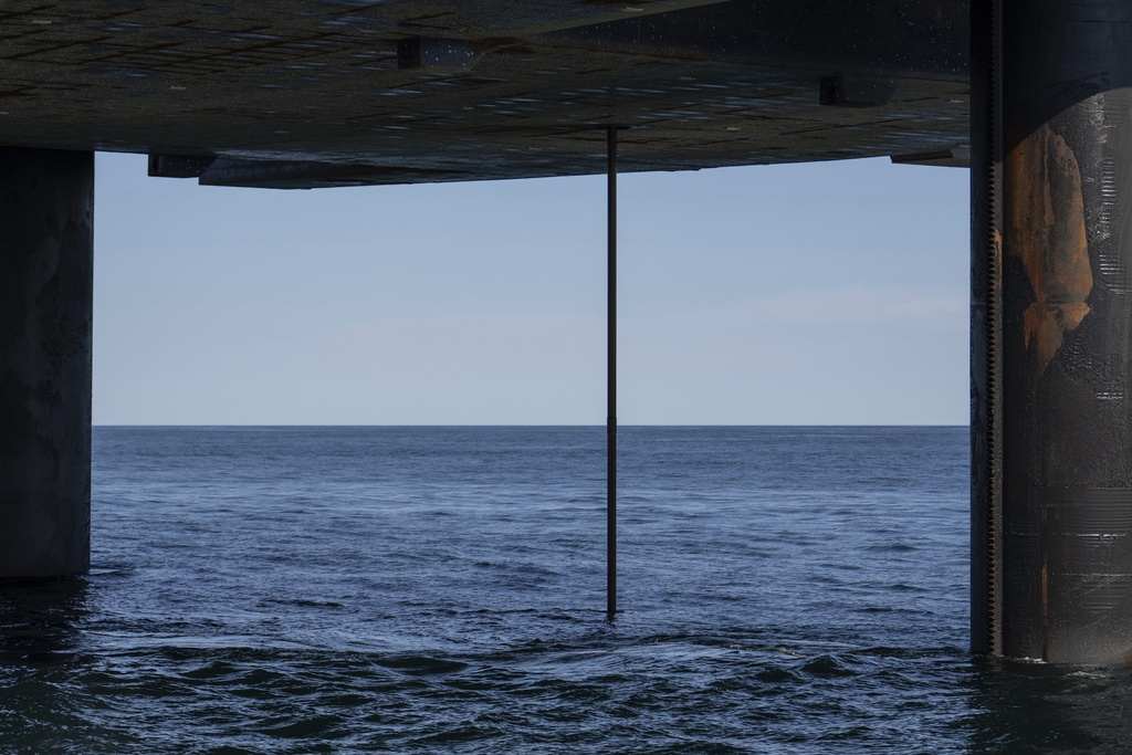 The wireline drilling core barrel is visible from the underside of the Liftboat Robert platform, from the Gaspee, a crew transport vessel, in the North Atlantic, Saturday, July 19, 2025. (AP Photo/Carolyn Kaster)