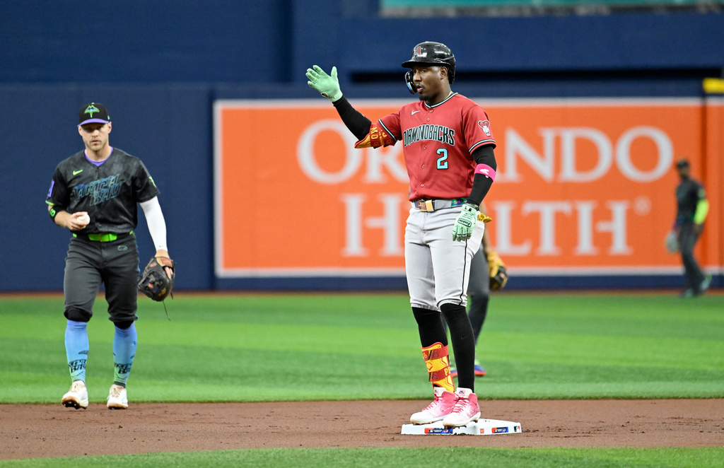 Tampa Bay Rays shortstop Taylor Walls, left, holds the ball as Arizona Diamondbacks' Geraldo Perdomo (2) celebrates after hitting a double during the first inning of a baseball game Saturday, June 27, 2026, in St. Petersburg, Fla. (AP Photo/Jason Behnken)