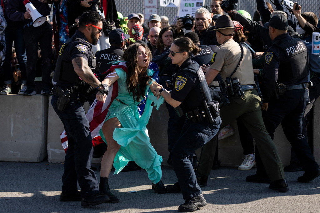Broadview police officers detain an activist dressed like the Statue of Liberty as dozens of protesters gather near the U.S. Immigration and Customs Enforcement facility in Broadview, Ill., Friday, Oct. 17, 2025. (Ashlee Rezin /Chicago Sun-Times via AP)