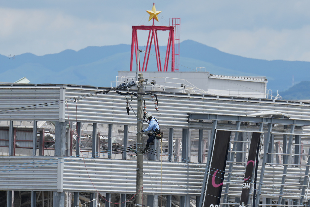 A utility worker repairs power lines near AEON Mall, which was damaged in an explosion following an earthquake in Kashima, Kumamoto Prefecture, southern Japan, Wednesday, July 29, 2026. (AP Photo/Hiro Komae)