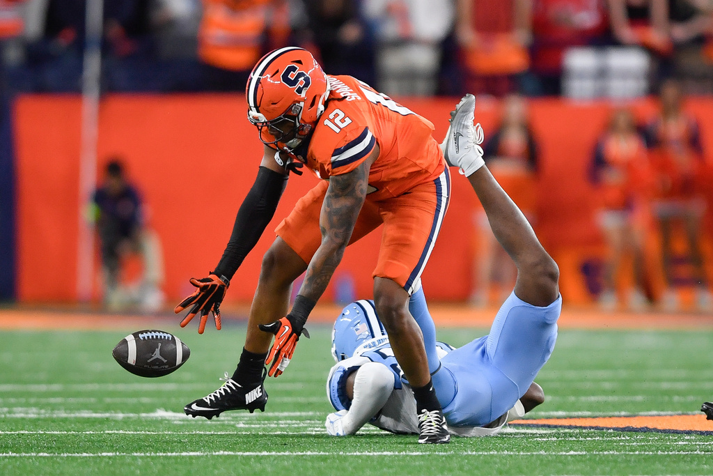 Syracuse linebacker Anwar Sparrow (12) picks up a fumble by North Carolina tight end Shamar Easter, bottom, and returns it for a touchdown during the first half of an NCAA college football game Friday, Oct. 31, 2025, in Syracuse, N.Y. (AP Photo/Adrian Kraus)