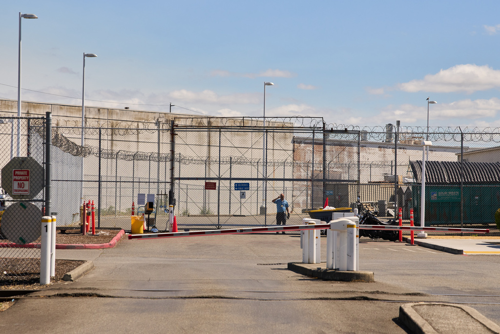 A GEO Group guard looks on from behind the fence at the Northwest U.S. Immigration and Customs Enforcement Processing Center, Aug. 13, 2025, in Tacoma, Wash. (AP Photo/Lindsey Wasson)