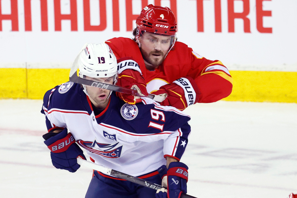 Columbus Blue Jackets' Adam Fantilli, front, is checked by Calgary Flames' Rasmus Andersson during first period NHL hockey action in Calgary on Wednesday, Nov. 5, 2025. (Larry MacDougal/The Canadian Press via AP)