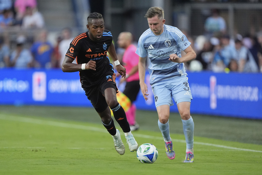 New York City FC forward Andres Perea (8) and Sporting Kansas City defender Andrew Brody (3) chase the ball during the first half of an MLS soccer match Saturday, July 19, 2025, in Kansas City, Kan. (AP Photo/Charlie Riedel)
