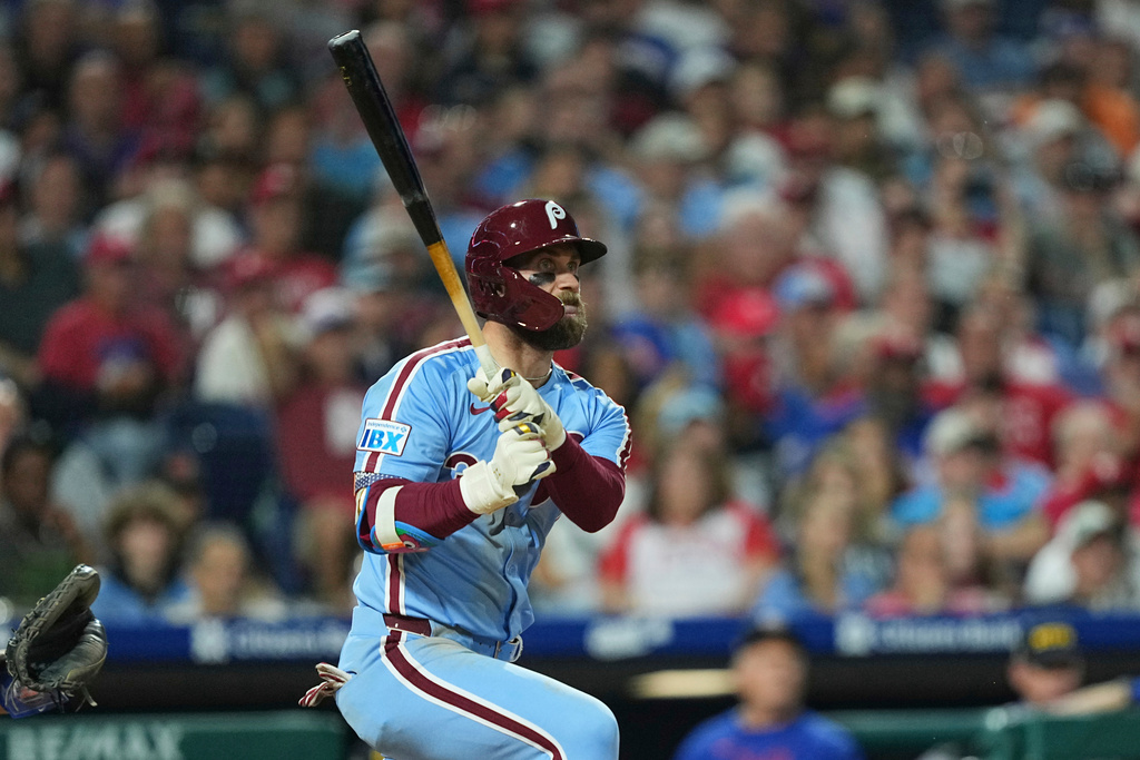 Philadelphia Phillies' Bryce Harper follows through after hitting an RBI double off of New York Mets pitcher David Peterson during the fifth inning of a baseball game, Thursday, Sept. 11, 2025, in Philadelphia. (AP Photo/Matt Rourke)