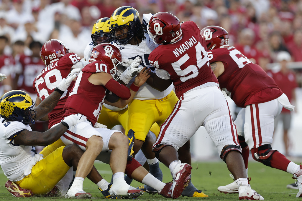 Oklahoma quarterback John Mateer (10) is stopped by Michigan linebacker Ernest Hausmann, center, during the first half of an NCAA college football game Saturday, Sept. 6, 2025, in Norman, Okla. (AP Photo/Alonzo Adams)