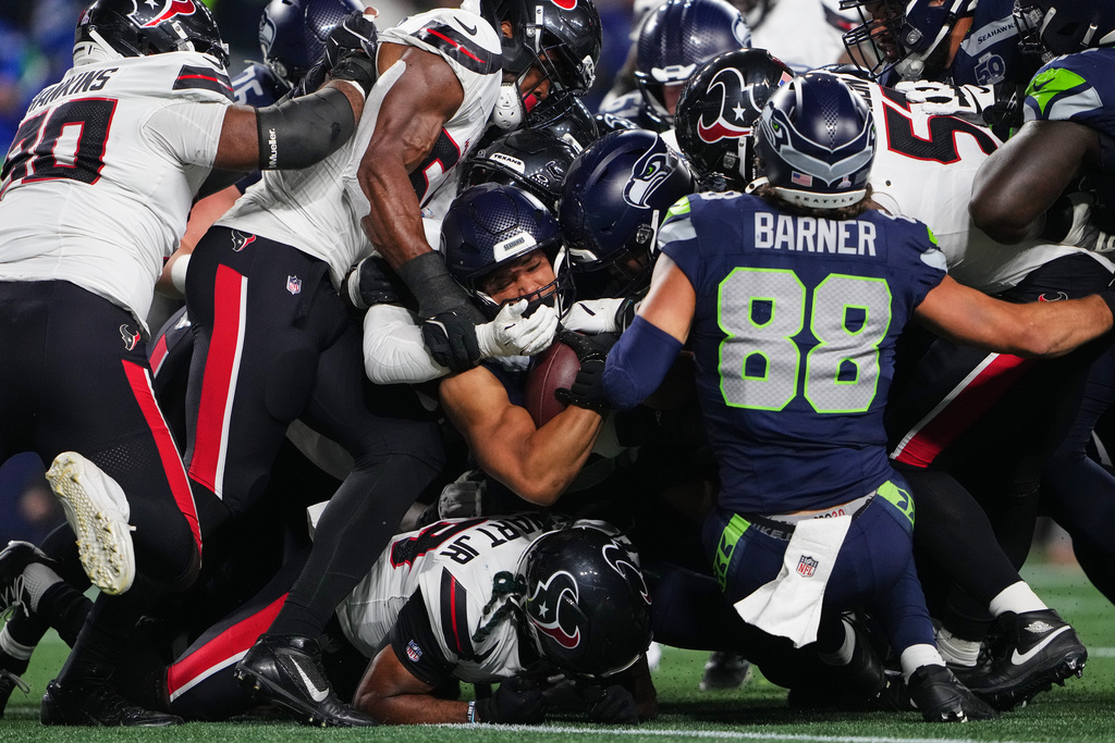 Seattle Seahawks running back Zach Charbonnet, center holding ball, scores a touchdown on a running play as the Houston Texans defend in the first half of an NFL football game Monday, Oct. 20, 2025, in Seattle. (AP Photo/Lindsey Wasson)