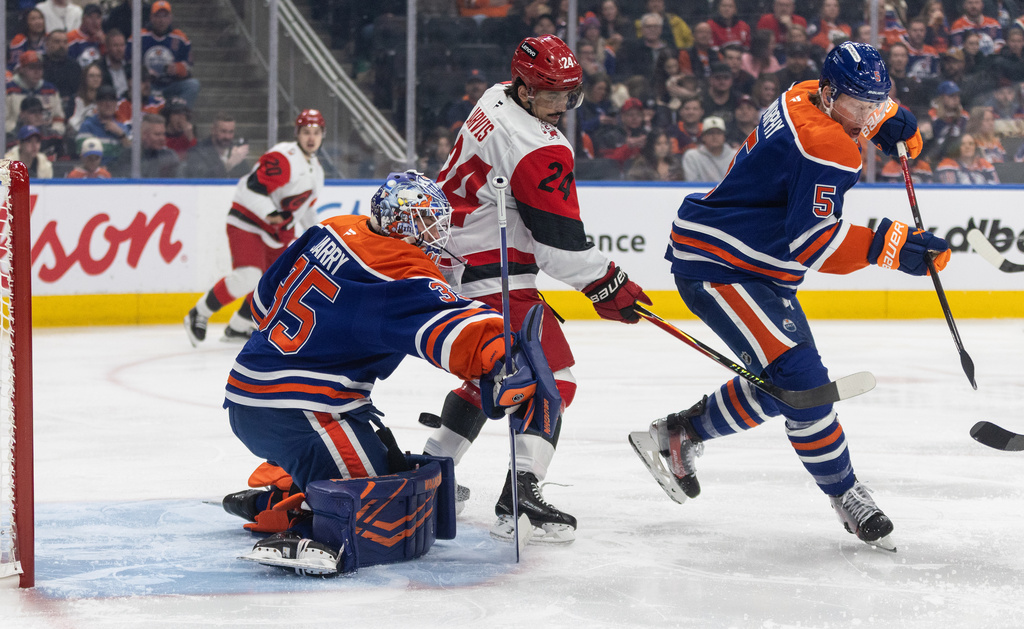 Carolina Hurricanes' Seth Jarvis (24) and Edmonton Oilers' Connor Murphy (5) battle as Oilers goalie Tristan Jarry (35) makes a save during first-period NHL hockey game action in Edmonton, Alberta, Friday March 6, 2026. (Jason Franson/The Canadian Press via AP)