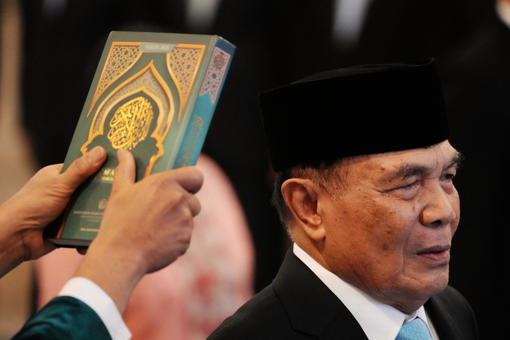 An Islamic cleric holds a holy book of Quran over the head of the newly-appointed Coordinating Minister for Political and Security Affairs Djamari Chaniago during the swearing-in ceremony at the presidential palace in Jakarta, Indonesia , Wednesday, Sept. 17, 2025. (AP Photo/Achmad Ibrahim)