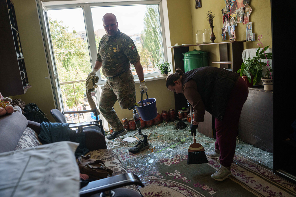 Oleksii, a Ukrainian war veteran, clears broken glass inside an apartment building damaged by a Russian drone strike in Kyiv, Ukraine, Tuesday, Sept. 22, 2026. (AP Photo/Evgeniy Maloletka)
