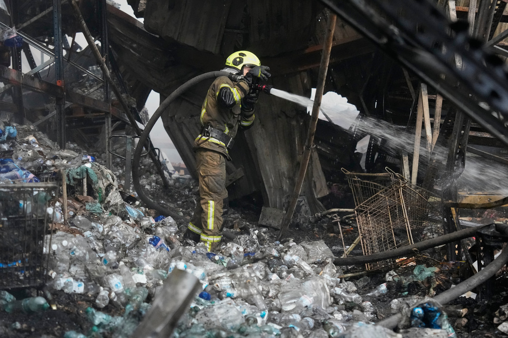A firefighter puts out a fire after Russian missiles hit a food warehouse near Kyiv, Ukraine, Wednesday, Aug. 5, 2026. (AP Photo/Efrem Lukatsky)