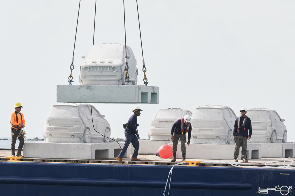 Workers prepare to submerge concrete cars that will be part of an underwater marine sculpture park off South Beach,Tuesday, Oct. 28, 2025, in Miami Beach, Fla. Native corals grown in a lab will be attached to the cars to create a reef. (AP Photo/Marta Lavandier)