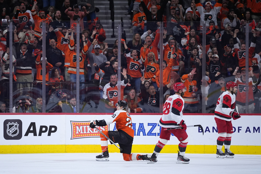 Philadelphia Flyers' Alex Bump, left, celebrates past Carolina Hurricanes' Jordan Martinook, center, and Sean Walker, right, after scoring a goal during the third period of Game 4 in a second-round NHL hockey Stanley Cup playoff series Saturday, May 9, 2026, in Philadelphia. (AP Photo/Matt Slocum)