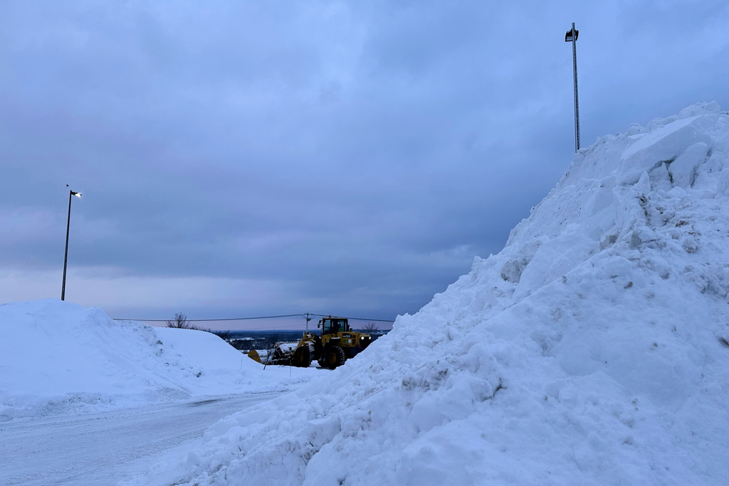 A snowplow works among piles of snow in Lowville, N.Y., on Thursday, Jan. 22, 2026. (AP Photo/Cara Anna)