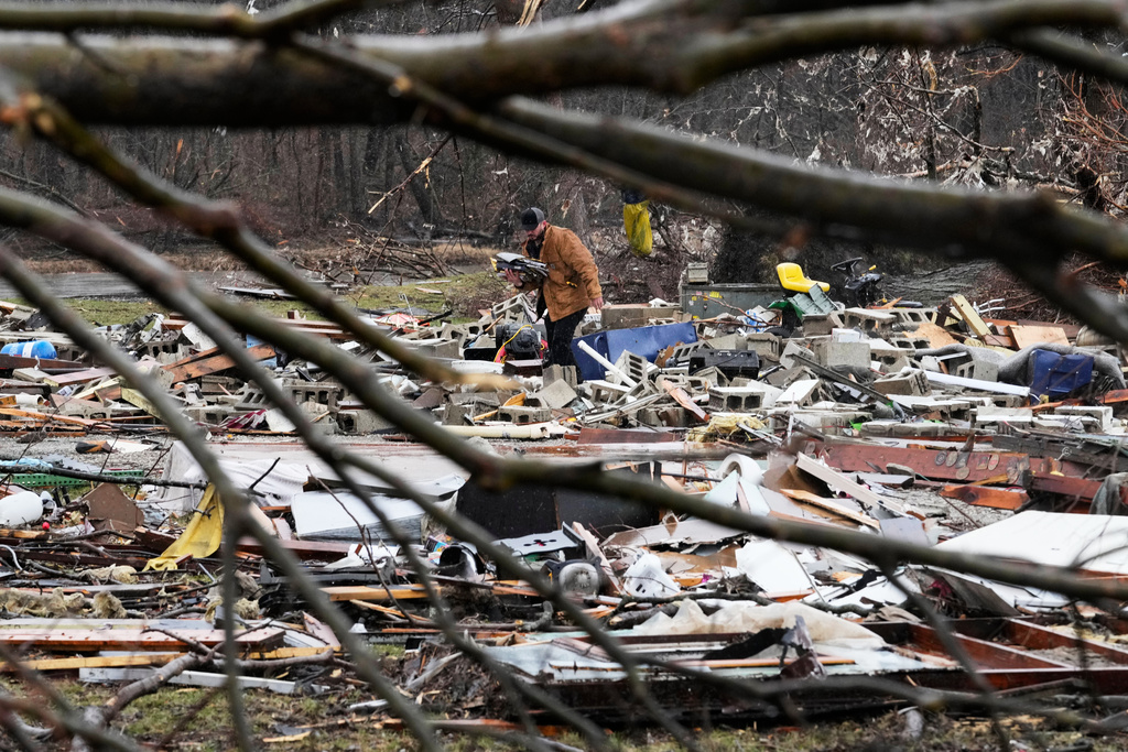 A person searches through his belongings amid debris in the aftermath of a powerful storm that ripped through the area a day earlier, in Aroma Park, Ill., Wednesday, March 11, 2026. (AP Photo/Nam Y. Huh)