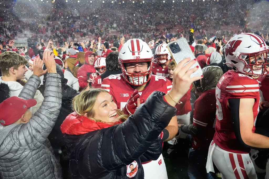 Wisconsin players celebrate as fans storm the field after an NCAA college football game against Washington Saturday, Nov. 8, 2025, in Madison, Wis. (AP Photo/Morry Gash)