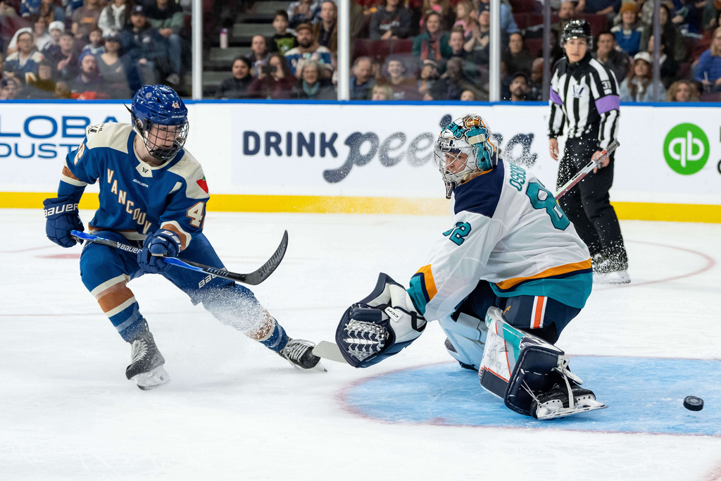Vancouver Goldeneyes' Claire Thompson, left, watches as the puck gets by New York Sirens goaltender Kayle Osborne (82) during the first period of a PWHL hockey game in Vancouver, British Columbia, Saturday, Dec. 6, 2025. (Ethan Cairns/The Canadian Press via AP)