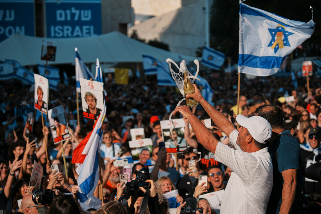 People react as they gather to watch a live broadcast of Israeli hostages released from Gaza at a plaza known as hostages square in Tel Aviv, Israel, Monday, Oct. 13, 2025. (AP Photo/Emilio Morenatti)