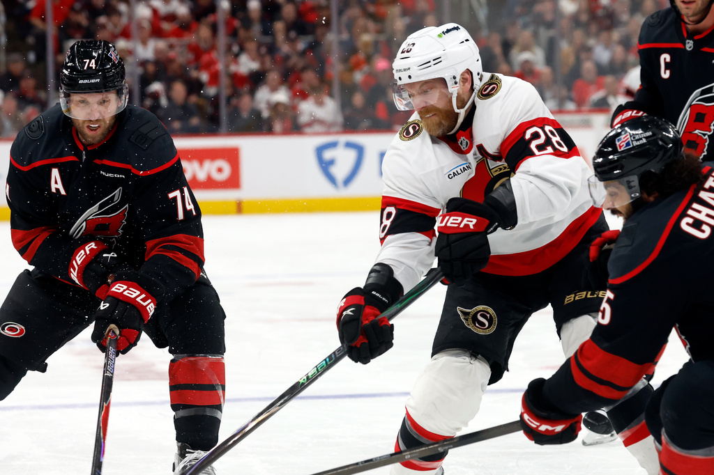Ottawa Senators' Claude Giroux (28) battles for the puck with Carolina Hurricanes' Jalen Chatfield, right, and Jaccob Slavin (74) during the first period of Game 2 of an NHL hockey Stanley Cup first-round playoff series in Raleigh, N.C., Monday, April 20, 2026. (AP Photo/Karl DeBlaker)