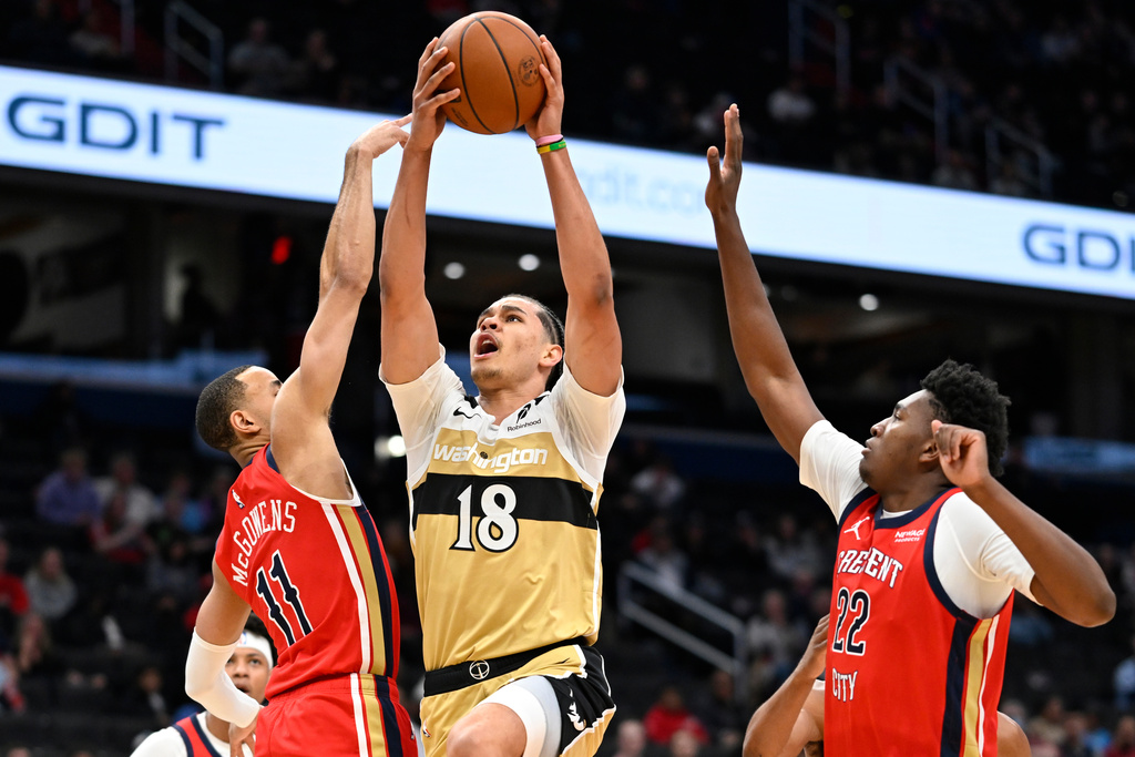Washington Wizards forward Kyshawn George (18) goes to shoot between New Orleans Pelicans guard Bryce McGowens (11) and center Derik Queen (22) during the first half of an NBA basketball game, Friday, Jan. 9, 2026, in Washington. (AP Photo/John McDonnell)