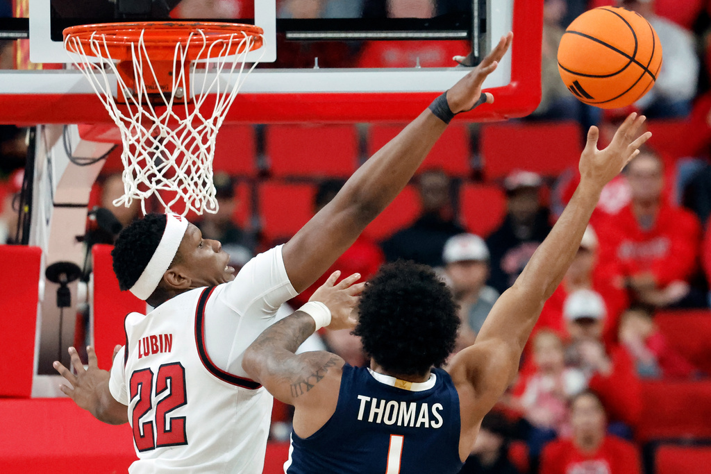 North Carolina State's Ven-Allen Lubin (22) tries to block the shot of Virginia's Malik Thomas (1) during the first half of an NCAA college basketball game in Raleigh, N.C., Saturday, Jan. 3, 2026. (AP Photo/Karl DeBlaker)