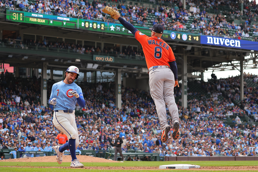 Houston Astros infielder Christian Walker jumps for the throw as Chicago Cubs' Dansby Swanson runs to first base during the eighth inning of a baseball game on Friday, May 22, 2026, in Chicago. (AP Photo/Melissa Tamez)