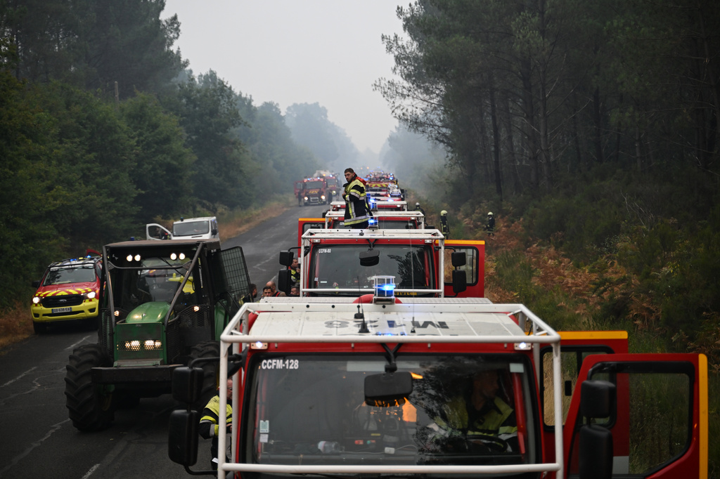 A firefighter stands on a truck on a road near Lacanau, southwestern France, Saturday, July 25, 2026, as wildfires rage in the area. (AP Photo/Emma Da Silva)